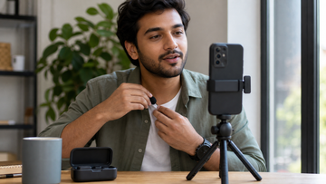 Creator clipping a compact wireless microphone while recording video on a smartphone