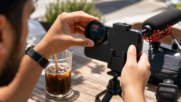 Close-up of a creator attaching an ND filter to a smartphone video rig