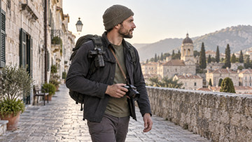 Travel photographer using a backpack camera clip and a cross-body camera strap